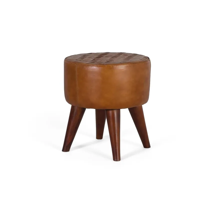 Este taburete redondo tiene un diseño elegante y refinado, está tapizado en piel bovina de un tono camel suave, que le otorga una textura suave y un aspecto cálido. La parte superior del asiento presenta un detalle decorativo distintivo. - Muebles
